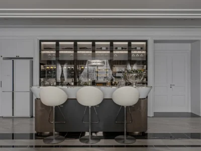 Moderne Bartheke als Teil einer stilvollen Inneneinrichtung in einer Wohnung, mit eleganten Barhockern, beleuchteten Glasregalen und hochwertiger Ausstattung – luxuriöses Wohnambiente.