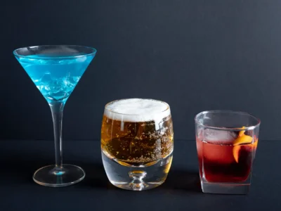 Auswahl an Shortdrinks – blauer Cocktail, Bier und roter Drink auf schwarzem Hintergrund für kreative Cocktail-Inspiration