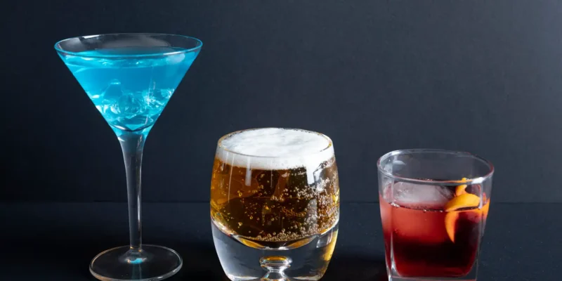 Auswahl an Shortdrinks – blauer Cocktail, Bier und roter Drink auf schwarzem Hintergrund für kreative Cocktail-Inspiration